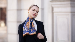 Model wearing a ladies narrow silk scarf in rich royal blue with gold equestrian-inspired detailing, styled neatly at the neck with a tailored navy blazer and white shirt.