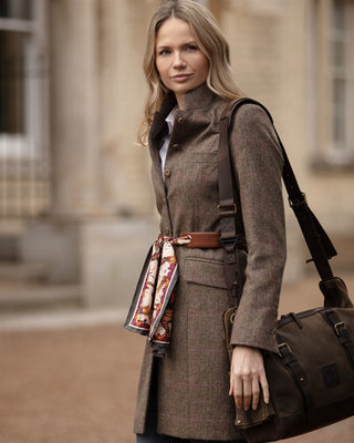 Woman in a brown coat with a bag, wrapped with a leather scarf belt and Clare Haggas George & Friends scarf.