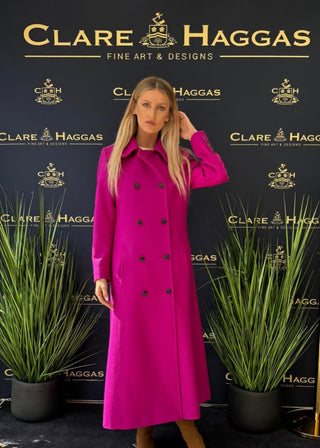 Woman in a pink coat standing in front of a Clare Haggas backdrop