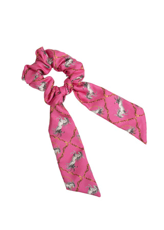 Pink scrunchie with tails, showing a horse pattern, displayed on a white background